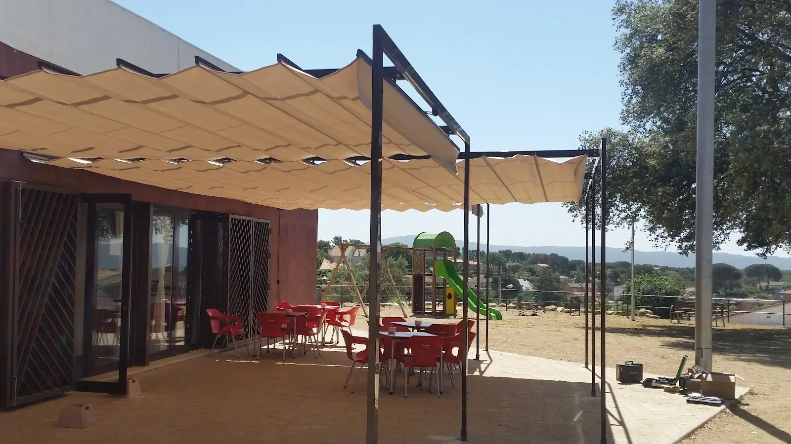 Pérgola con toldo plegable dando sombra a una terraza con mesas